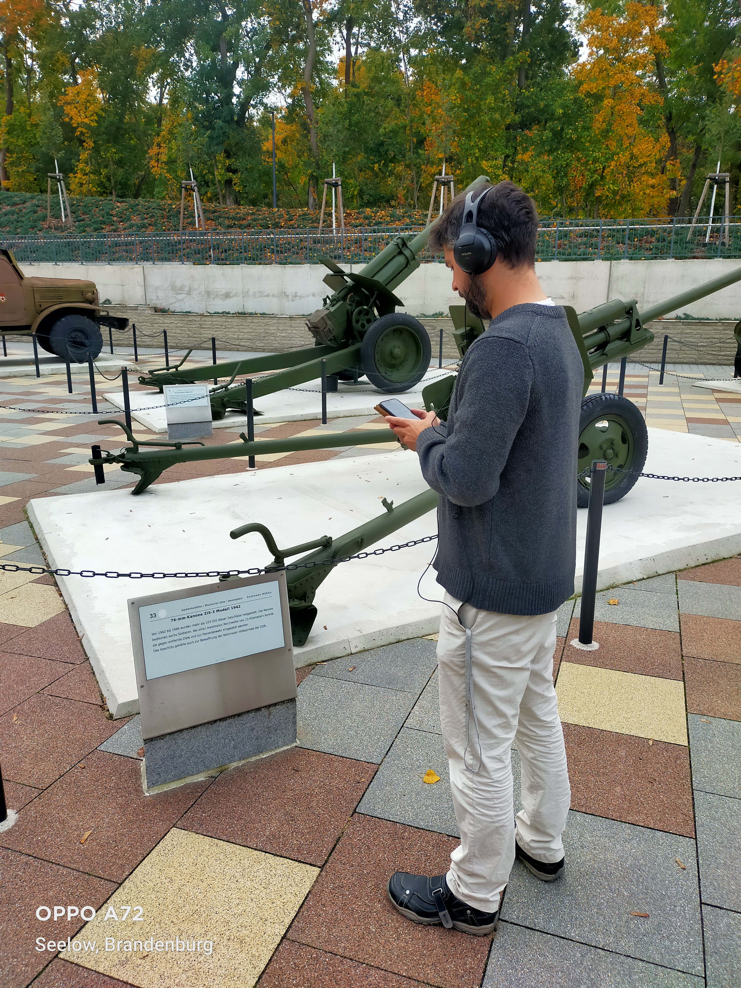 Ein Besucher mit Kopfhörern steht vor einem Exponat und hört sich einen eingesprochenen Text dazu an