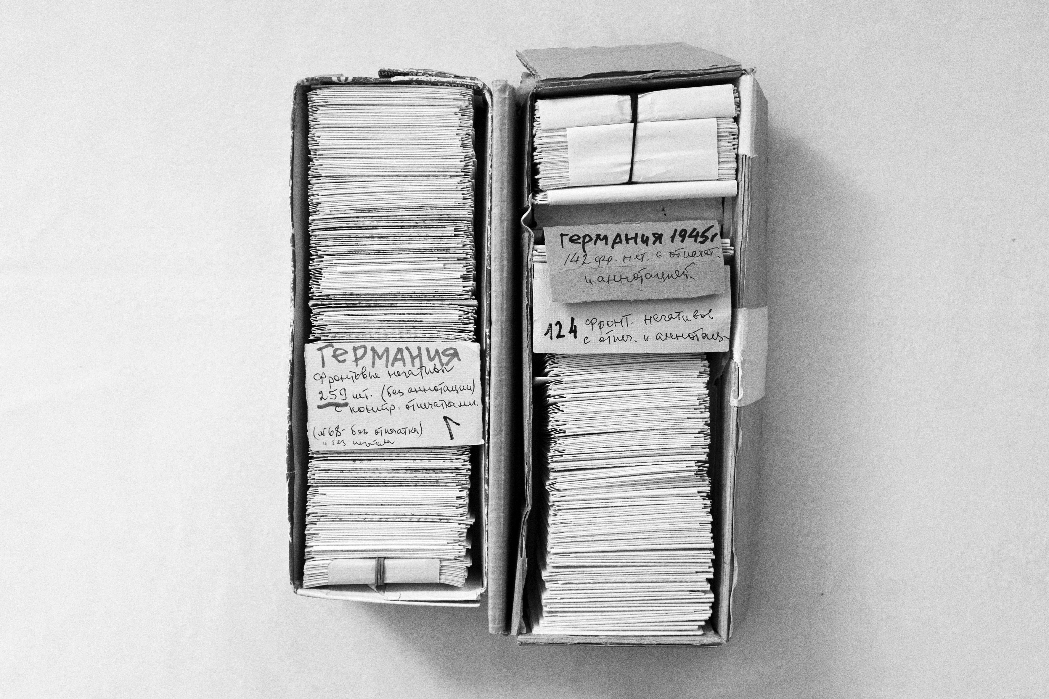 In zwei länglichen Kartons lagern viele Foto-Negative. Drei Pappschilder beschreiben auf Russisch grob den Inhalt der Kartons
